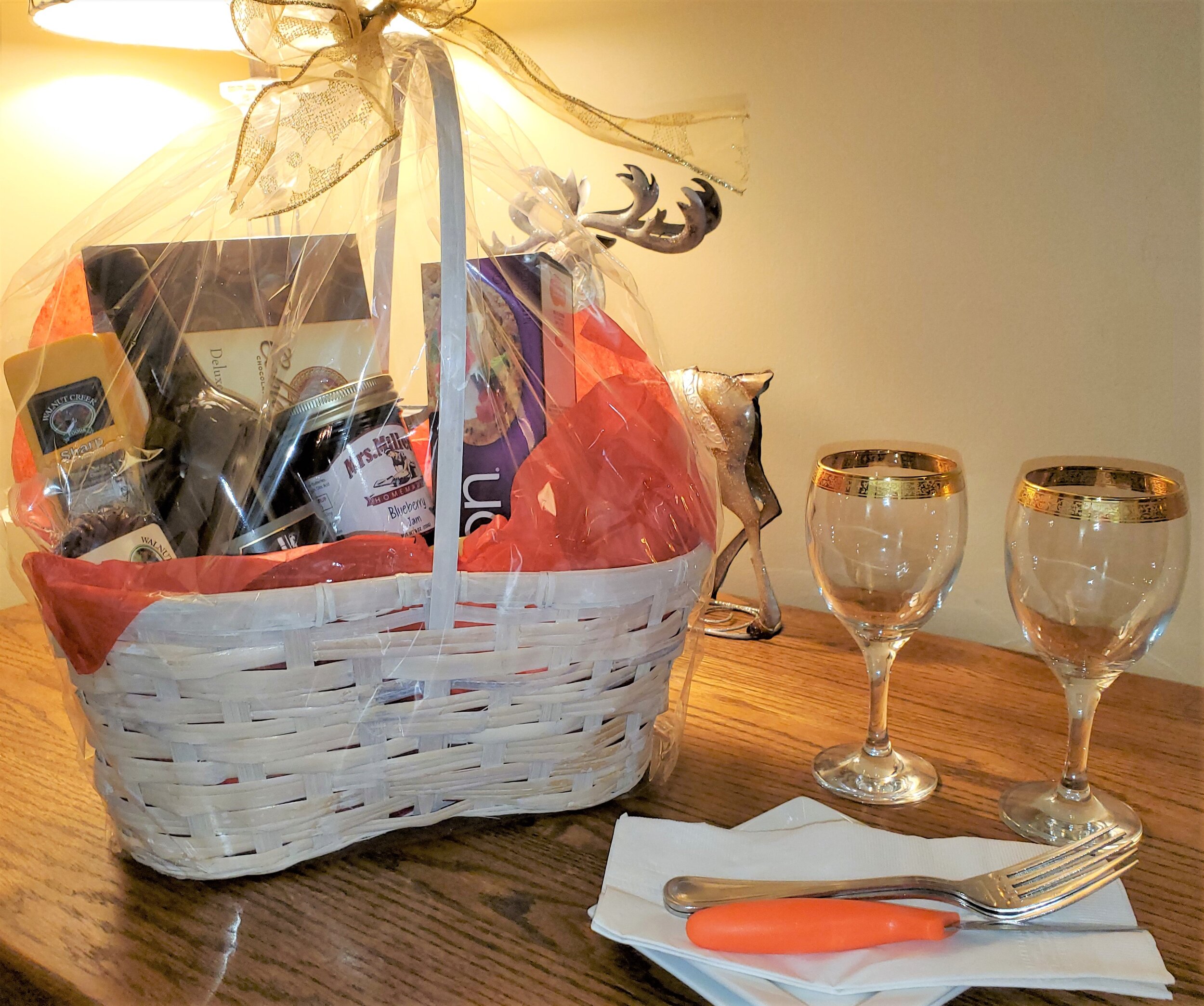 A wrapped gift basked on a table with wine glasses